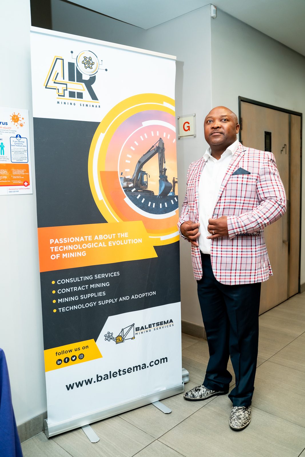 Founder standing beside the 4IRinMining and Baletsema banners